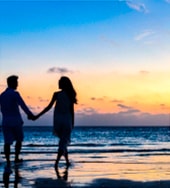 Foto ilustrativa de um casal andando na praia ao pôr do sol | Psicóloga em Santos – Joyce Mello